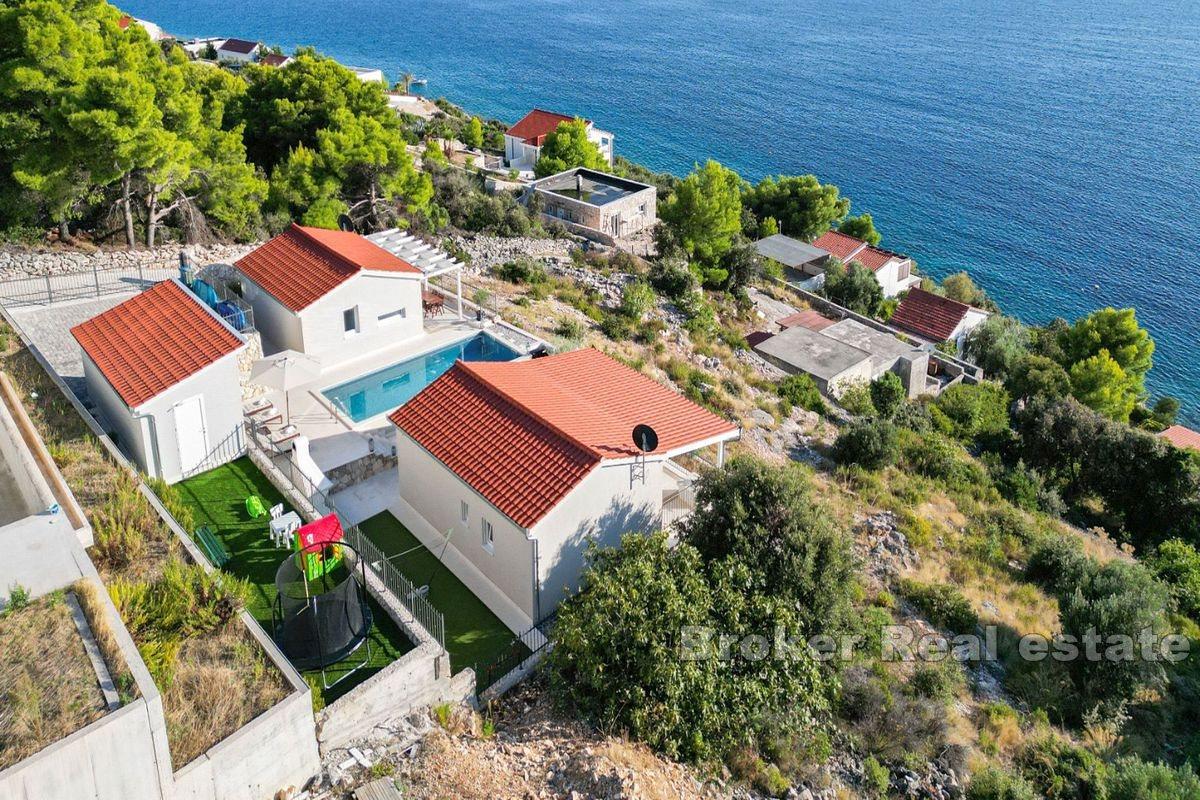 Two smaller houses with a pool and a view of the sea