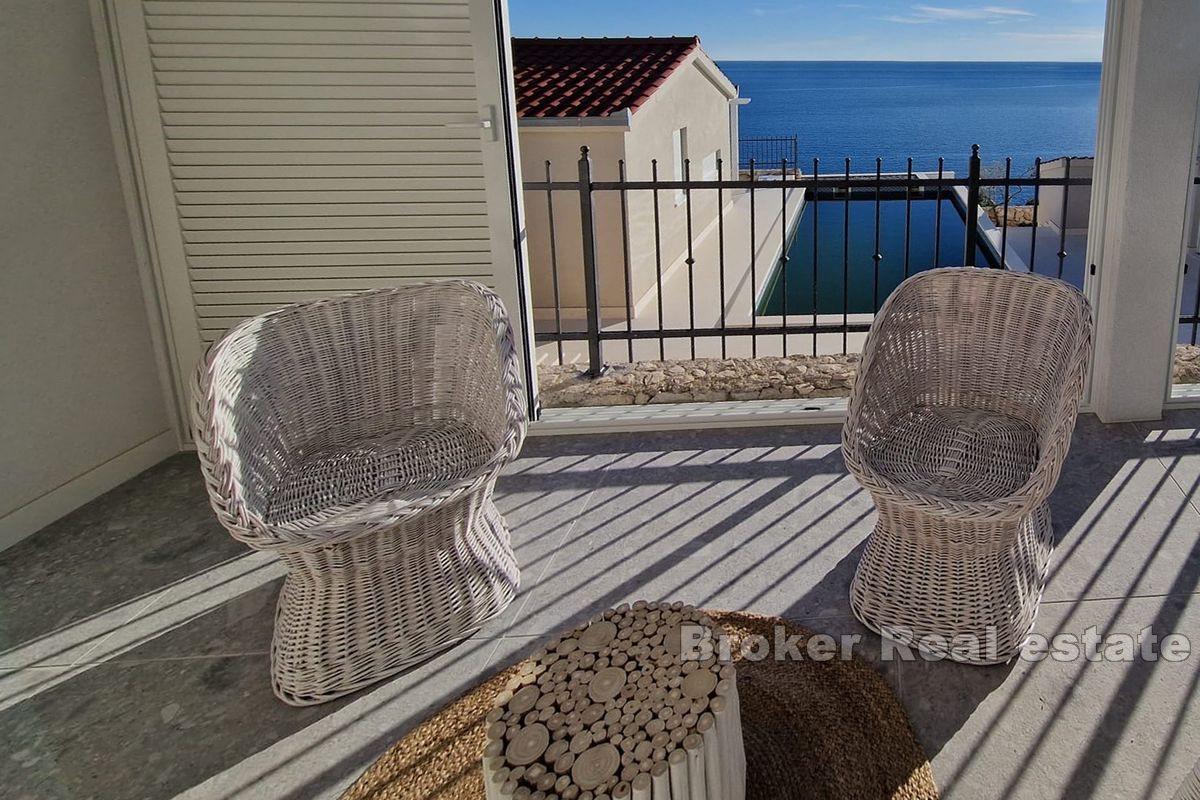 Two smaller houses with a pool and a view of the sea