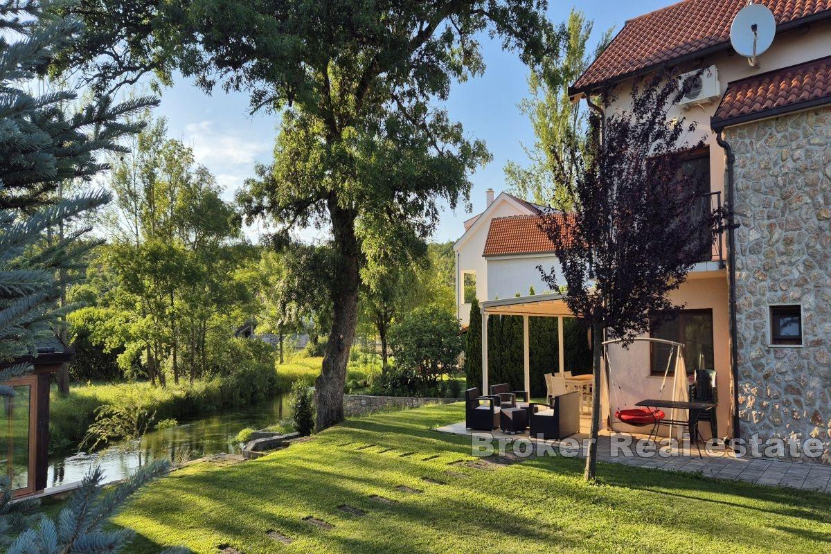 Fristående hus vid floden med pool och anlagd trädgård
